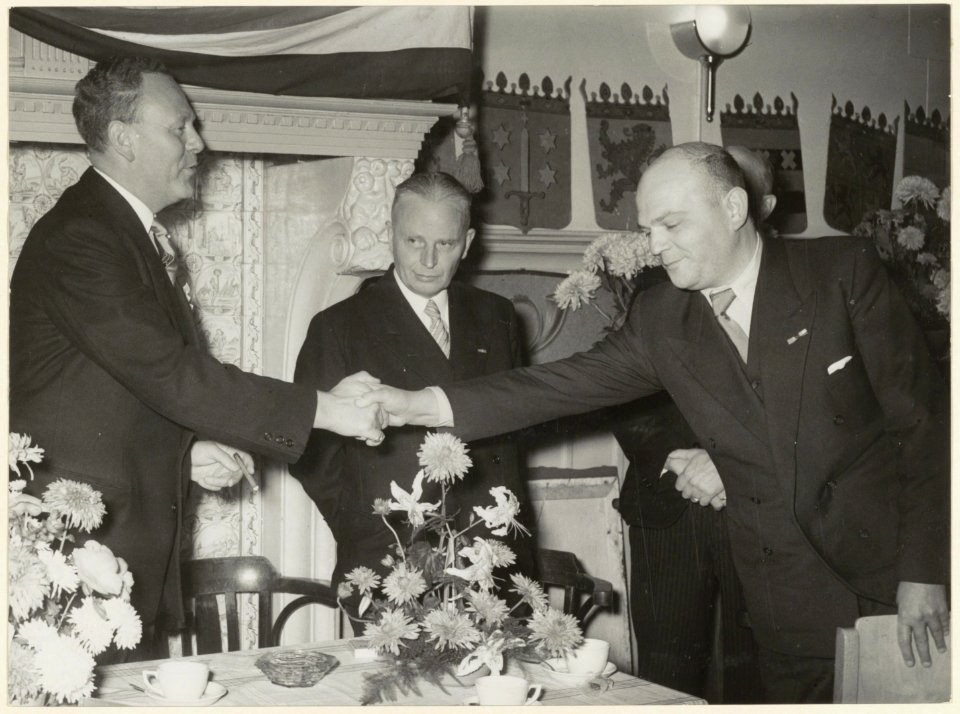 De voorzitter van het Protestants Militair tehuis, Ds. J. Bronsgeest) (links), wordt gefeliciteerd met het 70-jarig bestaan in 1952. Jansweg 32-34. NL-HlmNHA 54004567