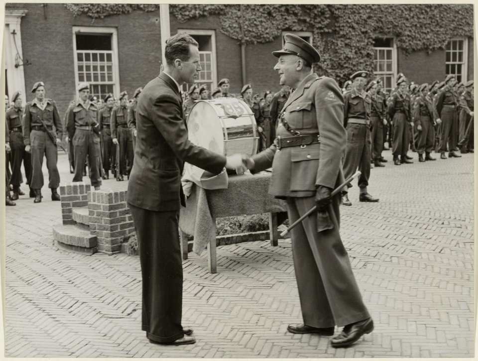 De voorzitter van de stichting Haarlems Bloei, de heer D.J.A. Geluk, overhandigt de lt.kolonel van het Haarlems garnizoen een drumstel. NL-HlmNHA 54004418