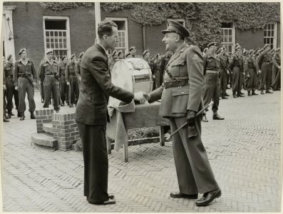 De voorzitter van de stichting Haarlems Bloei, de heer D.J.A. Geluk, overhandigt de lt.kolonel van het Haarlems garnizoen een drumstel. NL-HlmNHA 54004418
