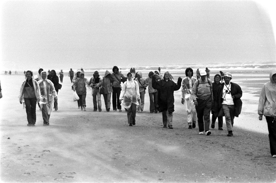 Deelnemers wandelen in de regen op het strand, Bestanddeelnr 928-0637
