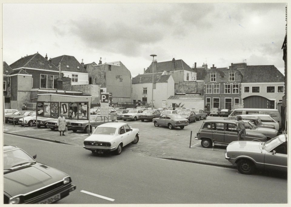 De parkeerplaats aan de Damstraat ziende naar de Berkenrodesteeg