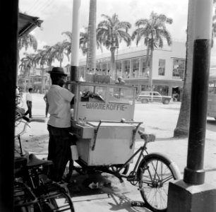 De Maagdenstraat in Paramaribo. Op de voorgrond een man met een koffiekarretje, Bestanddeelnr 252-4925