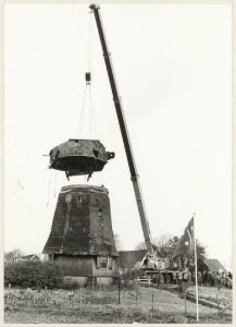 De renovatie van molen de Veer begint met het lichten van de kap met rechts de aanwezigen onder wie staatssecretaris G.C. Wallis de Vries die het startsein geeft
