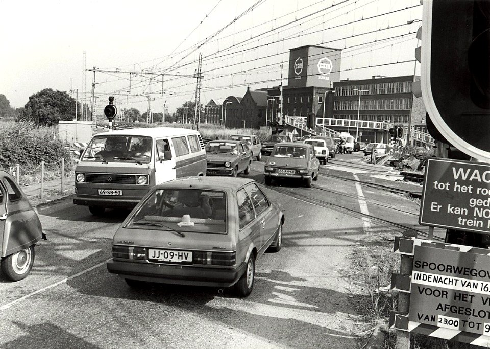 De spoorwegovergang bij de CSM suikerfabriek, ziende naar het zuidoosten. Aangekocht in 1984 van fotograaf C. de Boer. - Gepubliceerd in het Haarlems Dagblad van 30.11.1983. Identificatienum, NL-HlmNHA 1478 25900 K 38