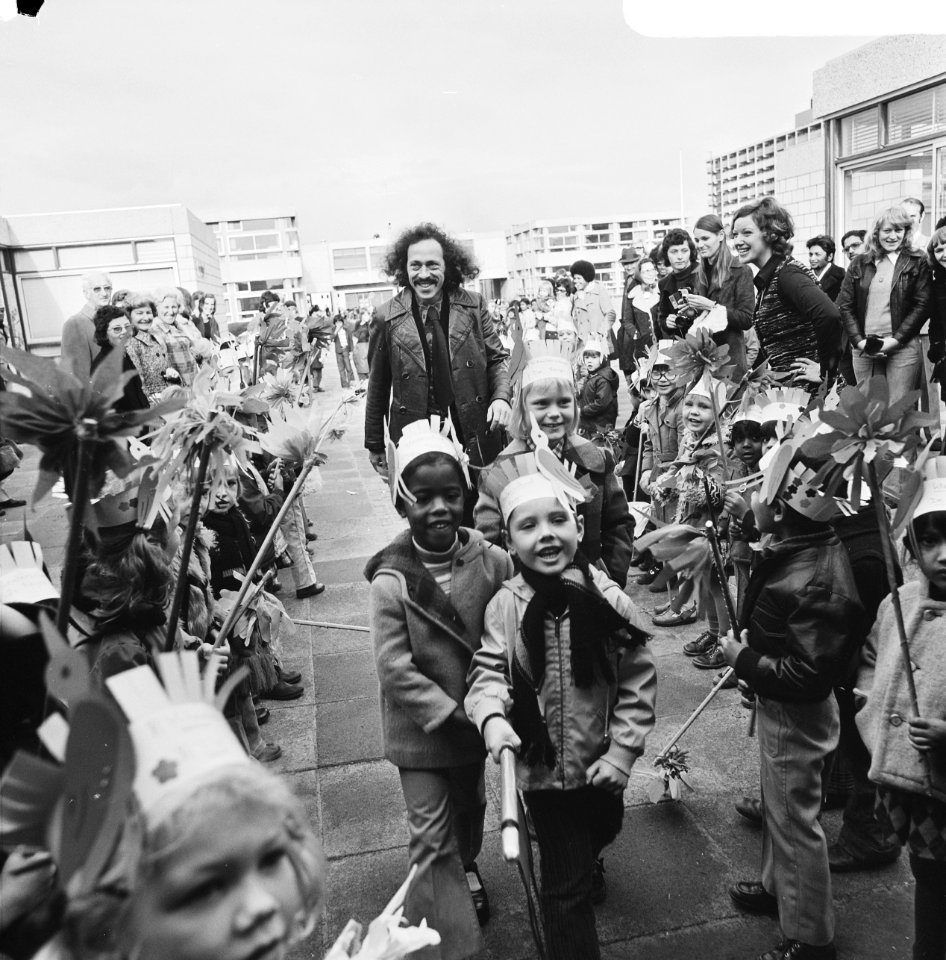 De wethouder temidden van leerkrachten en kinderen met feestmutsen, Bestanddeelnr 926-8094