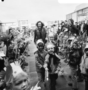 De wethouder temidden van leerkrachten en kinderen met feestmutsen, Bestanddeelnr 926-8094