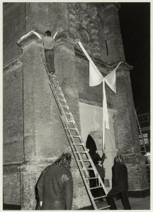 De toren van de Nieuwe Kerk wordt na de restauratie onthuld. De roze strik die door buurtbewoners om de toren was geknoopt, werd door gemeenteambtenaren van monumentenzorg niet echt op prijs, NL-HlmNHA 54011445