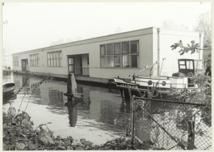 De schoolboot, 15 jaar in het Zuider Buiten Spaarne gelegen, wordt versleept en afgemeerd, ter hoogt van Droste en de Harmenjansweg waar de boot gaat diene als wijkcentrum De Brug. NL-HlmNHA 54009608
