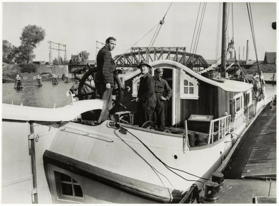 De schrijver Jan de Hartog (links) op zijn in Haarlem gebouwde tjalk, aan de Harmenjansweg 57bb bij de reparatiewerf voor schepen W.B. van Kuykhoven & Zn. In het midden staat Coen Kuykhoven