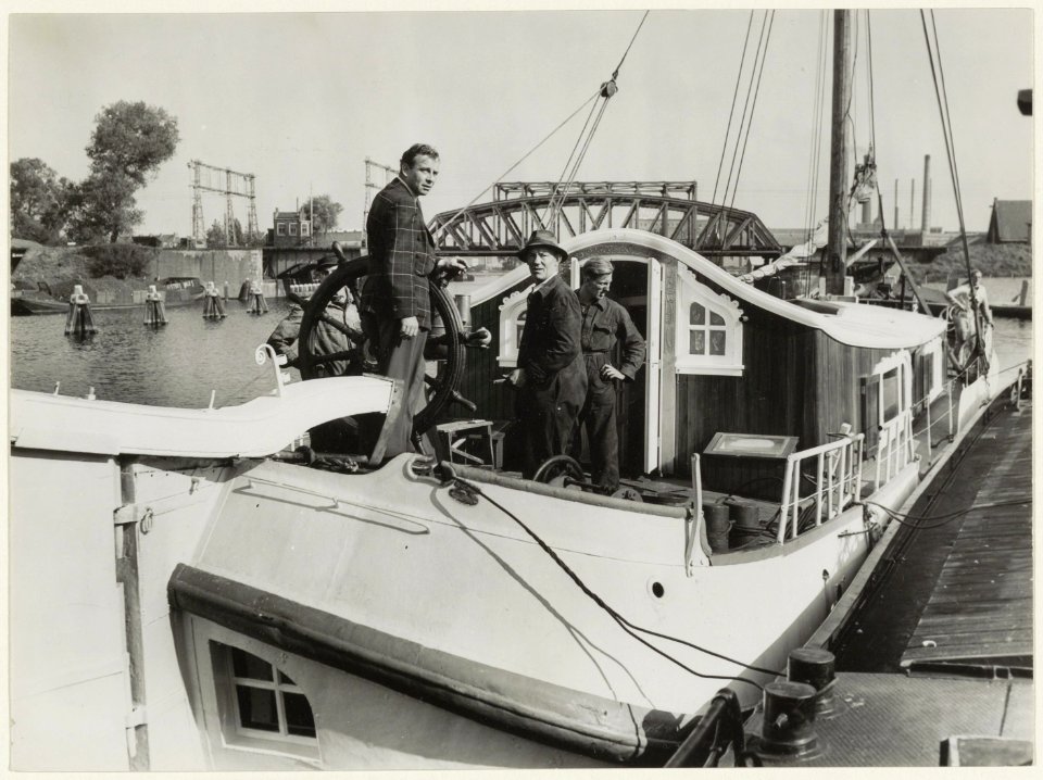De schrijver Jan de Hartog ( links ) op zijn in Haarlem gebouwde tjalk, op het Spaarne bij de spoorbrug. NL-HlmNHA 54005641