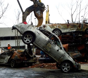 Demolition grabbing a burned car to haul away