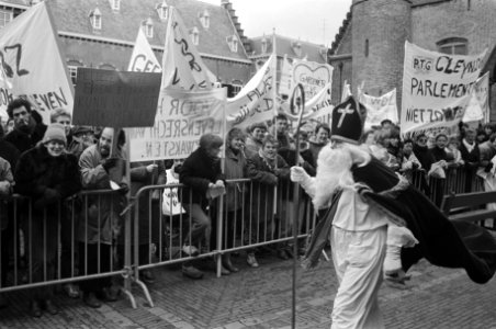 Demonstranten achter dranghekken kijken naar een voorbijkomende Sinterklaas, Bestanddeelnr 932-4955