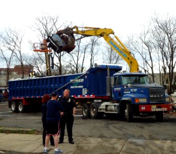 Demolition lifting burnt car to waste removal truck
