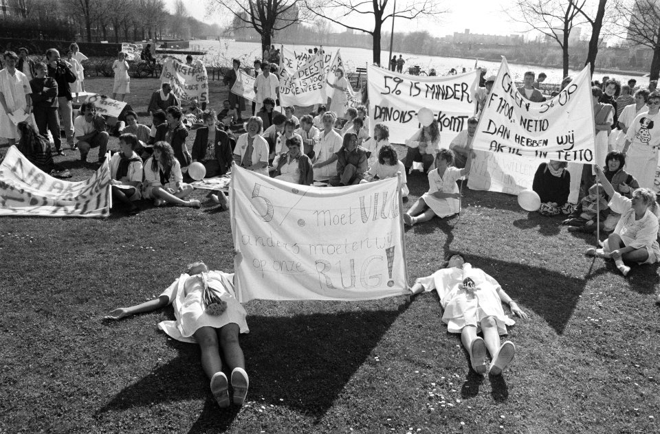 Demonstranten liggen en zitten op een grasveld met spandoeken, Bestanddeelnr 934-4306