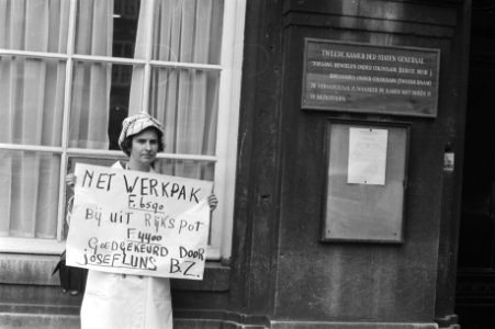 Demonstrante op het Binnenhof met een bord met de tekst Net werkpak F. 6590. B, Bestanddeelnr 924-5862