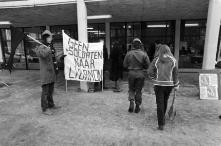 Demonstranten bij de samenkomst een spandoek draagt de tekst Geen soldaten naa, Bestanddeelnr 930-1394
