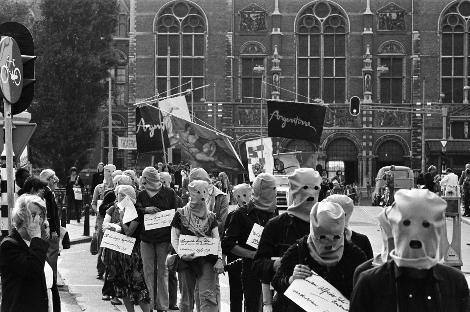 Demonstranten in Amsterdam, met kappen op, voeren in optocht spandoeken en borde, Bestanddeelnr 931-6770
