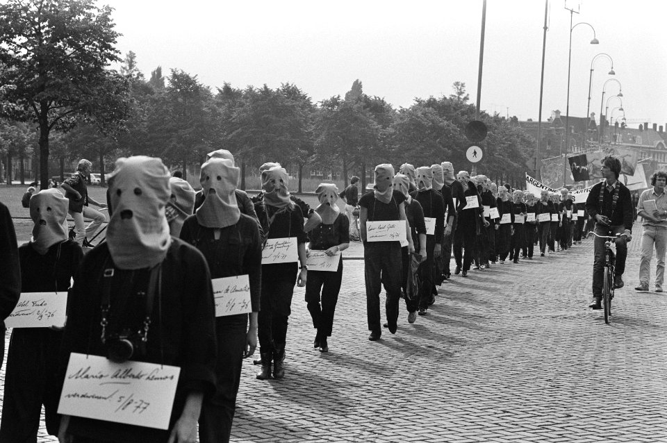 Demonstranten in Amsterdam, met kappen op, voeren in optocht met borden met daar, Bestanddeelnr 931-6769