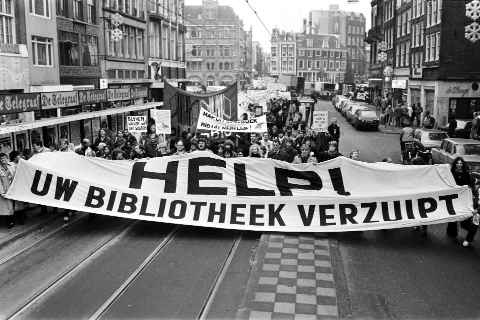 Demonstranten met spandoek Help uw bibliotheek verzuipt, Bestanddeelnr 932-7693
