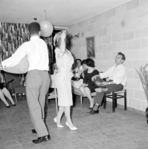 Dansende gastvrouw met een van de gasten terwijl ze een glazen vaas op haar scho, Bestanddeelnr 255-4332