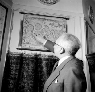 De heer Dellaert thuis wijzend op een plek in Zeeuws Vlannderen op een oude kaar, Bestanddeelnr 254-2450