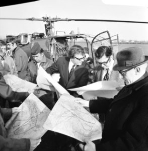De minister bekijkt, staand voor de helicopter, een kaart, Bestanddeelnr 927-0006