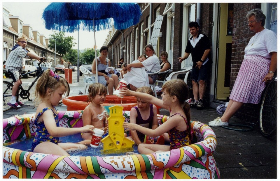 De kinderen uit de Harmenjanswijk vermaken zich tijdens een hittegolf in speelbadjes in de Damaststraat. NL-HlmNHA 54035194