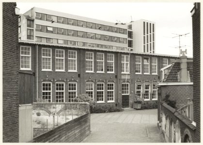 De Linschotenschool voor openbaar lager onderwijs in de Linschotenstraat tegen de achtergrond van het gebouw van Openbare Werken Koningstein aan het Zuider Buiten Spaarne. NL-HlmNHA 54010429