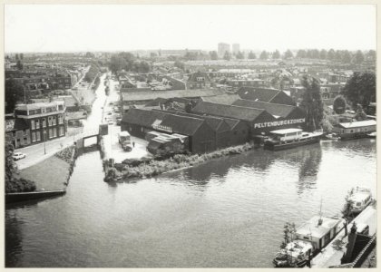 De loodsen van houthandel Peltenburg en Zonen, gezien vanuit het gemeentelijk bedrijf voor Openbare Werken aan de overzijde van het Spaarne. NL-HlmNHA 54004817