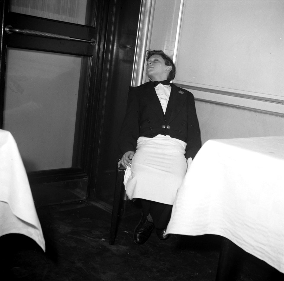 De kleinste en jongste ober slapend aan een tafel in restaurant Wivex, Bestanddeelnr 252-9189