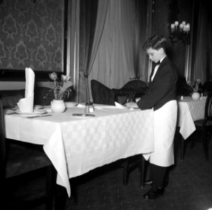 De kleinste en jongste ober dekt een tafel in restaurant Wivex, Bestanddeelnr 252-9191