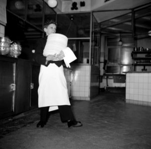 De kleinste en jongste ober met een stapel borden in de keuken van restaurant Wi, Bestanddeelnr 252-9185