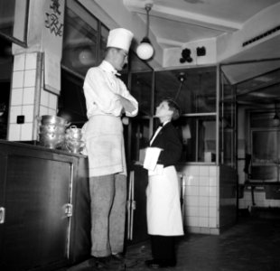 De kleinste en jongste ober naast een kok in de keuken van restaurant Wivex, Bestanddeelnr 252-9184