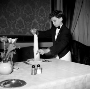 De kleinste en jongste ober dekt een tafel in restaurant Wivex, Bestanddeelnr 252-9193