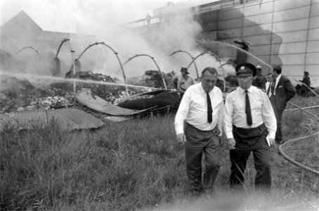 De eigenaar van het bedrijf, de heer Daniels met agent op terrein van de brand, Bestanddeelnr 921-5513