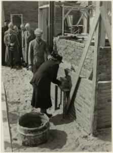 De echtgenote van wethouder Geluk, mevr.B.C. Geluk-van Dooren, metselt de eerste steen in de kleedkamer van het Openluchttheater. NL-HlmNHA 54005514