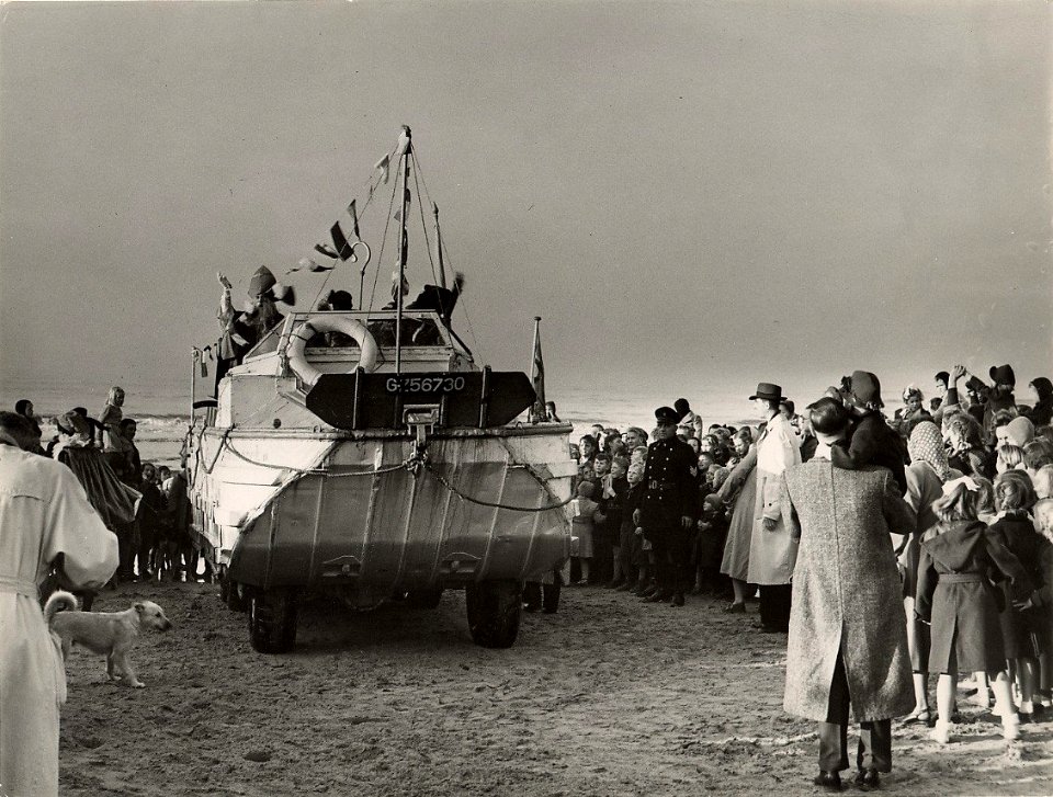 De aankomst op 26 november van Sint Nicolaas per amfibievoertuig (de duck uit de tweede wereldoorlog) op het strand. Aangekocht in 1977 van fotograaf C. de Boer. Identificatienummer 54-00553, NL-HlmNHA 1478 25900 K 38