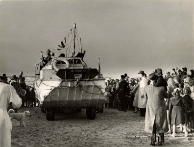 De aankomst op 26 november van Sint Nicolaas per amfibievoertuig (de duck uit de tweede wereldoorlog) op het strand. Aangekocht in 1977 van fotograaf C. de Boer. Identificatienummer 54-00553, NL-HlmNHA 1478 25900 K 38