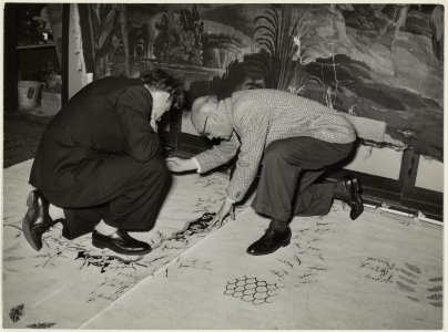 De franse tapijtontwerper Jean Lurçat (rechts) was in de werkplaats voor het herstellen van antieke tapijten te Haarlem, met zijn ontwerp voor het tapijt, dat aan het gemeentebestuur van Ein, NL-HlmNHA 54010760