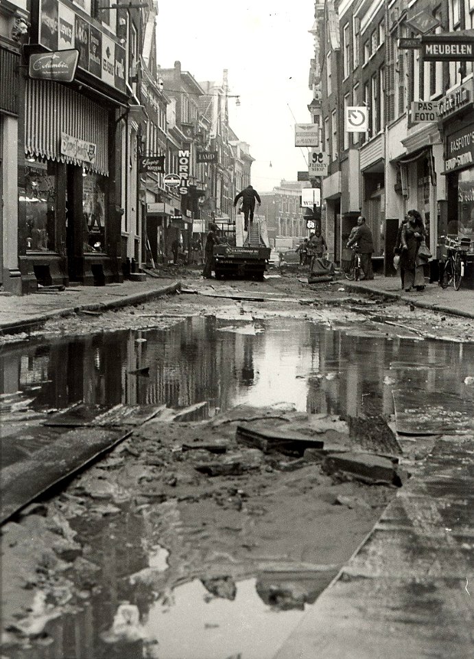De Barteljorisstraat bij de Grote Markt, ziende naar het noorden, werkzaamheden voor de aanleg van een sierbestrating. NB. Wateroverlast door een lek gestoten waterleidingbuis. Aangekocht in, NL-HlmNHA 54003811