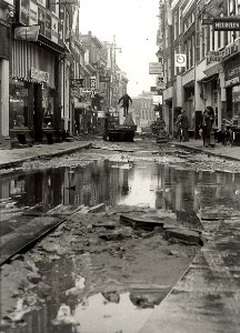 De Barteljorisstraat bij de Grote Markt, ziende naar het noorden, werkzaamheden voor de aanleg van een sierbestrating. NB. Wateroverlast door een lek gestoten waterleidingbuis. Aangekocht in, NL-HlmNHA 54003811