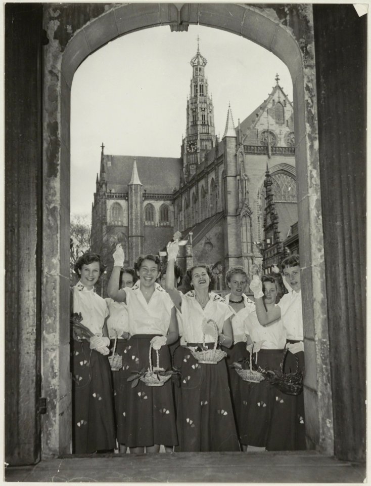 De Haarlemse bloemenmeisjes op de trap van het stadhuis met doorkijk naar de Grote Kerk. NL-HlmNHA 54010531