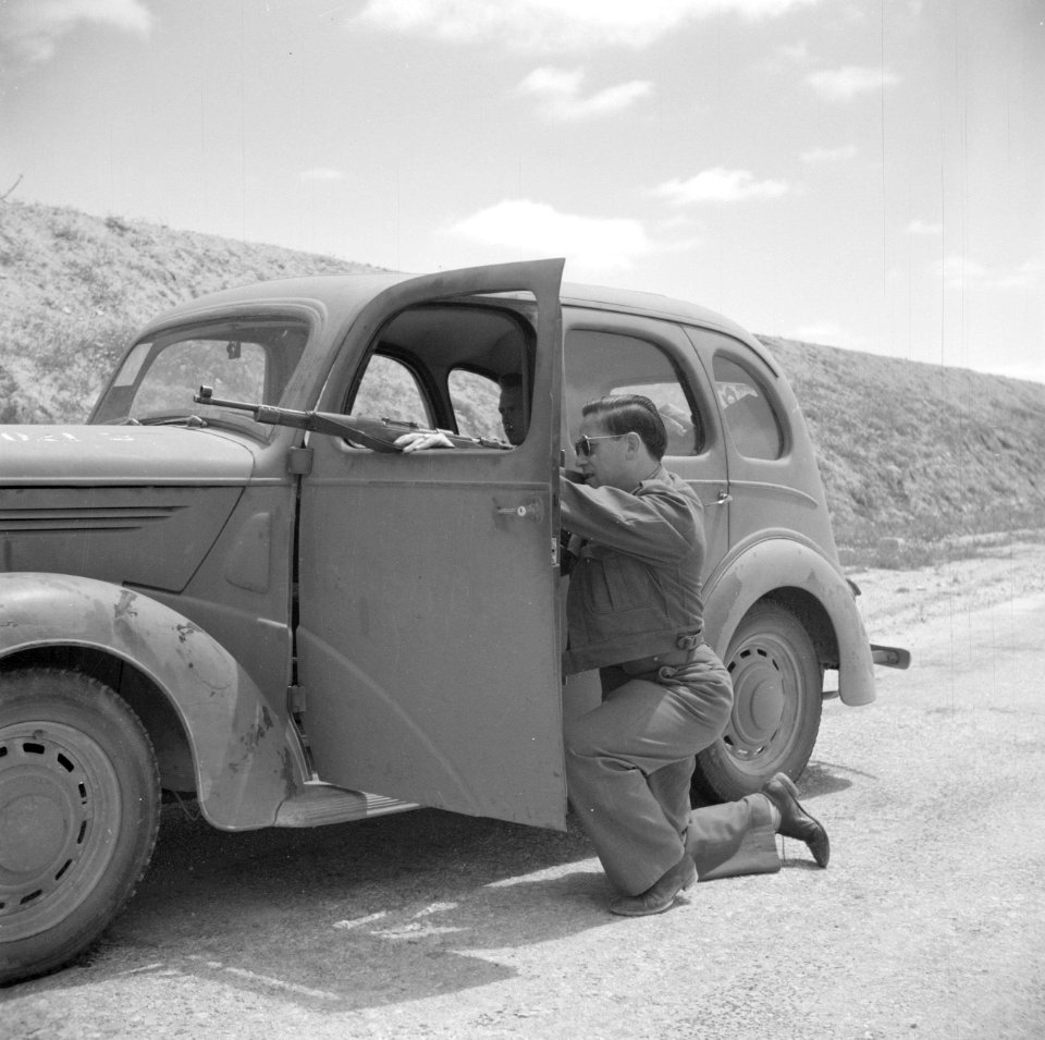De fotograaf in de Negevwoestijn. Chauffeur richt geknield zijn geweer door het , Bestanddeelnr 255-0772
