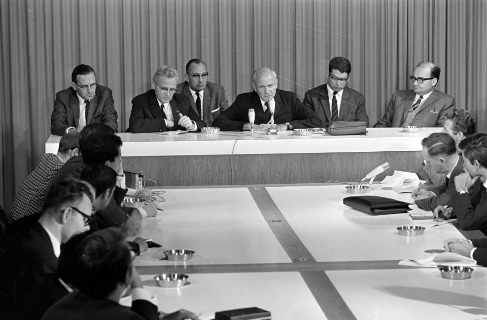De delegatie houdt op Schiphol een persconferentie. Vlnr. de heren Noteboom, Th…, Bestanddeelnr 921-6690