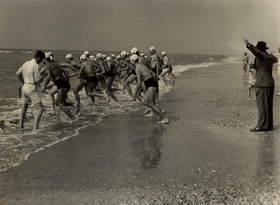 De deelnemers starten voor de 1 mijls zwemwedstrijd langs de kust van Zandvoort. Aangekocht in 1976 van fotograaf C. de Boer. Identificatienummer 54-010311, NL-HlmNHA 54010311