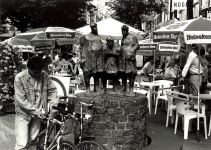 De Grote Houtstraat met het beeldje Winkelen of Stadten, met drie winkelende vrouwen. Aangekocht van United Photos de Boer bv. - Negatiefnummer 34941 k 26. - Gepubliceerd in het Haarlems Dagblad van 0