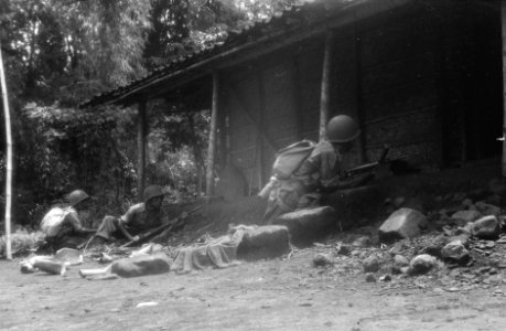 Drie KNIL-militairen lijken een huis te belegeren, ze liggen in dekking voor de, Bestanddeelnr 327