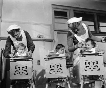 Drie baby's worden, gezeten in eetstoelen, gevoerd door twee verpleegsters, Bestanddeelnr 901-4152