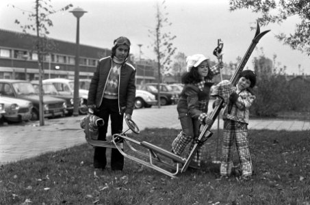 Drie kinderen, voorzien van wintersport attributen, showen de kleding, Bestanddeelnr 926-8085