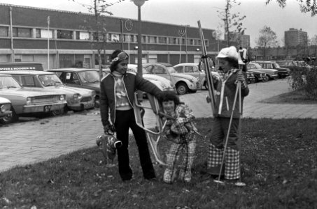 Drie kinderen, voorzien van wintersport attributen, showen de kleding, Bestanddeelnr 926-8082